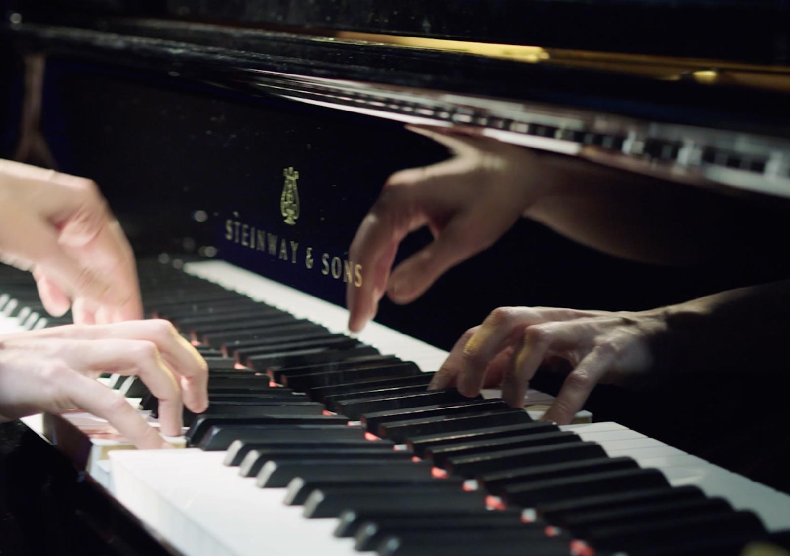 Handen op een Steinway & Sons vleugel tijdens een pianoles