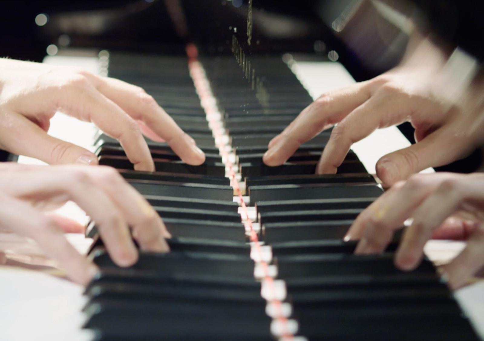 Four hands playing piano together