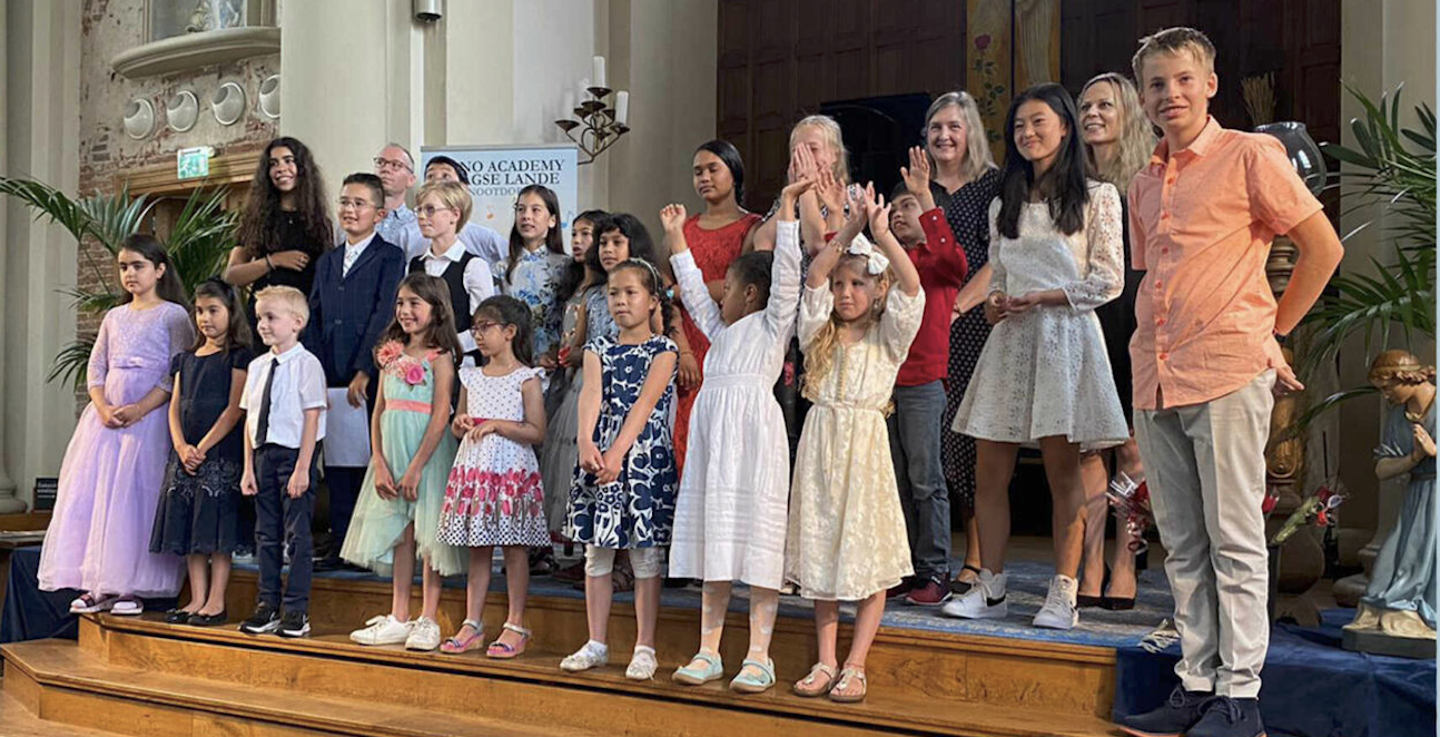 Younger students cheering on stage in the church during a summer concert by Piano Academy Haagse Lande.