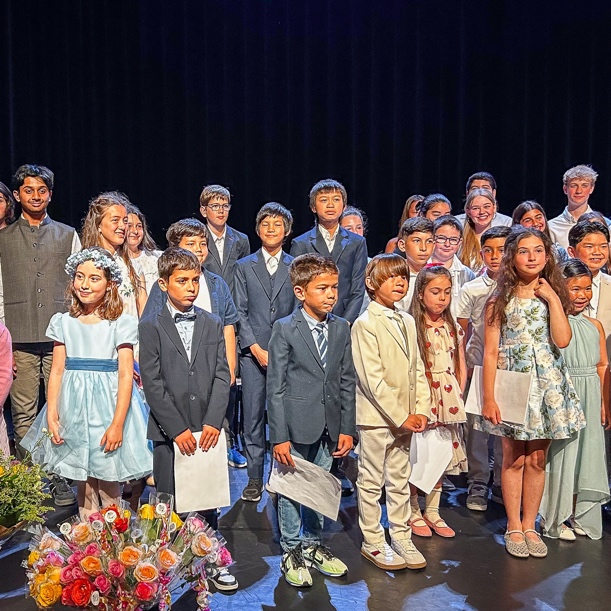 A group of children standing on stage with a bouquet of flowers in the foreground