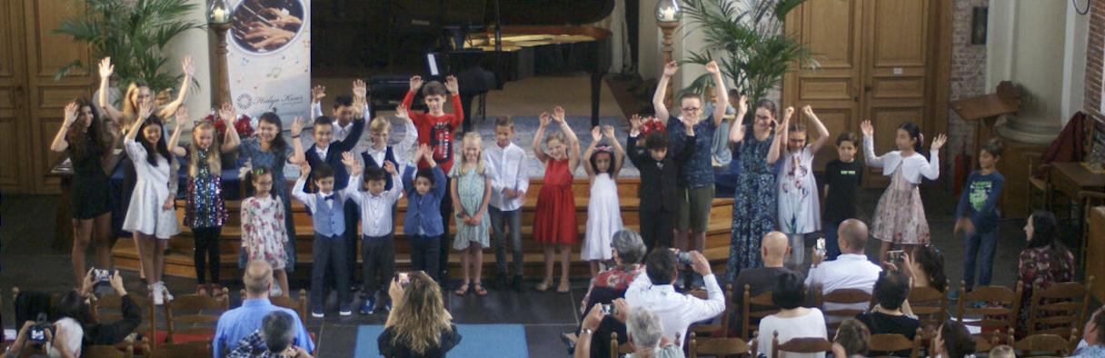 Children celebrating together after a summer concert performance in a church venue.